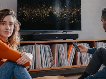 Frau und Mann im Wohnzimmer vor Sounddeck und TV